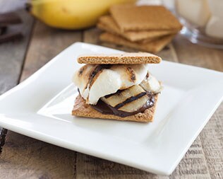 Smore with banana and drizzled chocolate on a white plate Smore with banana and drizzled chocolate on a white plate