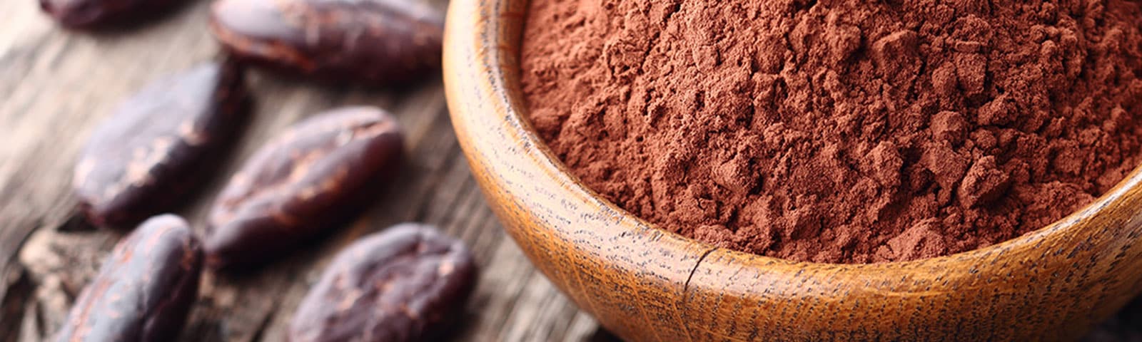 Cacao powder in a bowl next to nibs on a table