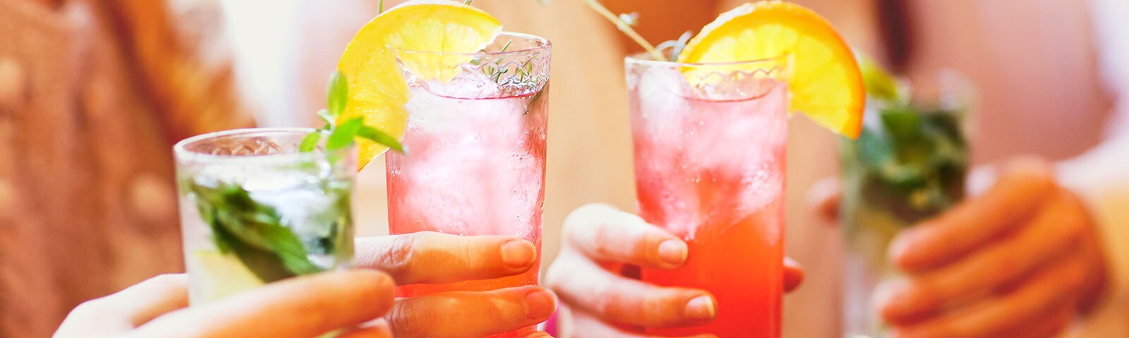 People in a group holding their mixed drinks People in a group holding their mixed drinks