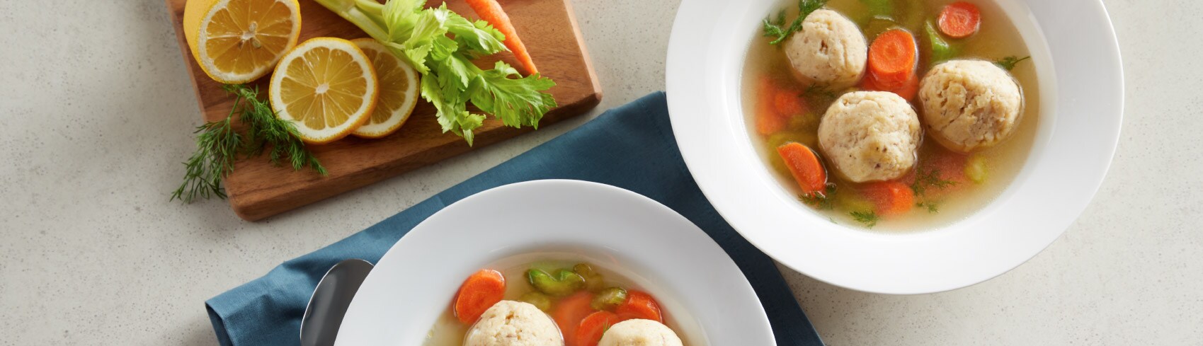 Matzo ball soup in a white bowl with fresh ingredients on the side Matzo ball soup in a white bowl with fresh ingredients on the side