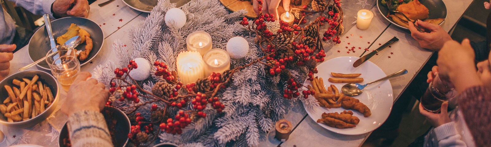 Fall decorated table with a candle centerpiece and people gathered around eating dinner Fall decorated table with a candle centerpiece and people gathered around eating dinner