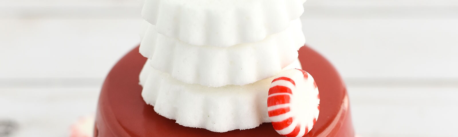 Stack of handmade bath bombs on a red stand with peppermint candies in the background Stack of handmade bath bombs on a red stand with peppermint candies in the background