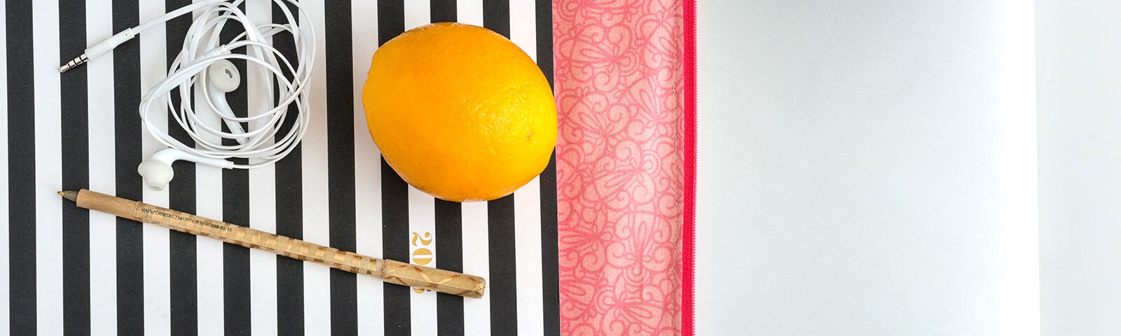 Lemon on top of black and white stripe tablecloth with ears buds and pen Lemon on top of black and white stripe tablecloth with ears buds and pen