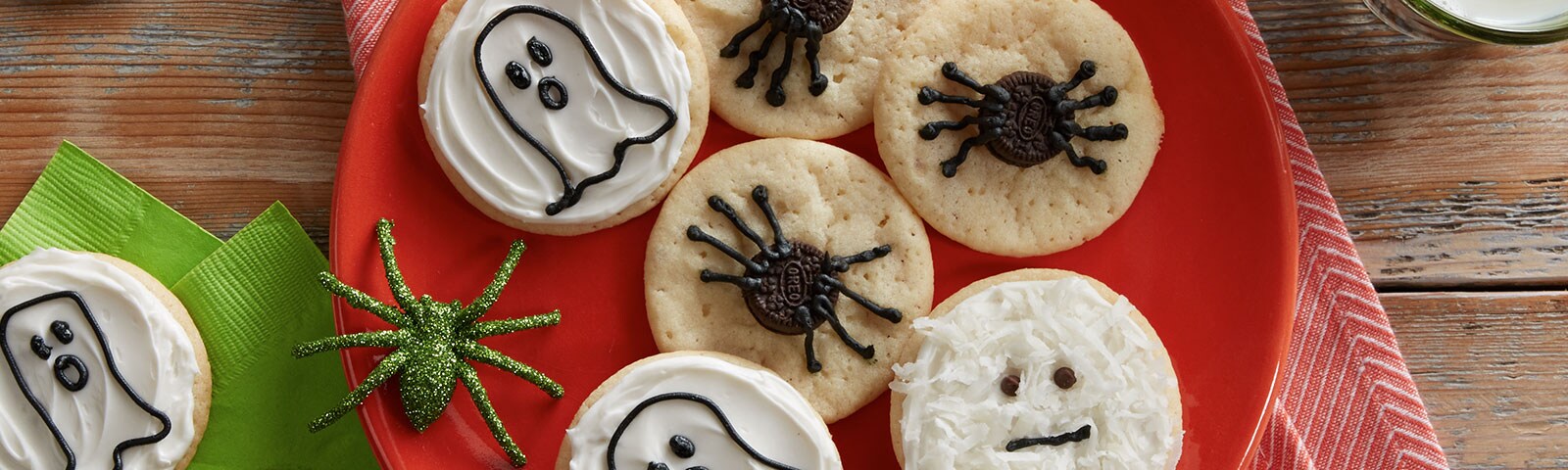 Halloween cookies on a plate. One decorated as a ghost with another decorated as a spider.