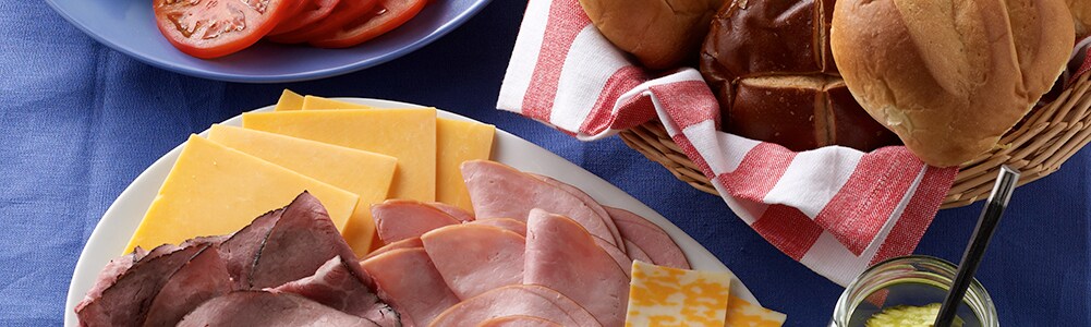Meats and cheeses, hamburger buns and veggie toppings on a platter Meats and cheeses, hamburger buns and veggie toppings on a platter