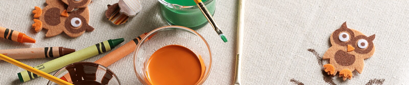 A DIY tabletop with crayons, fabric paint and owl stickers