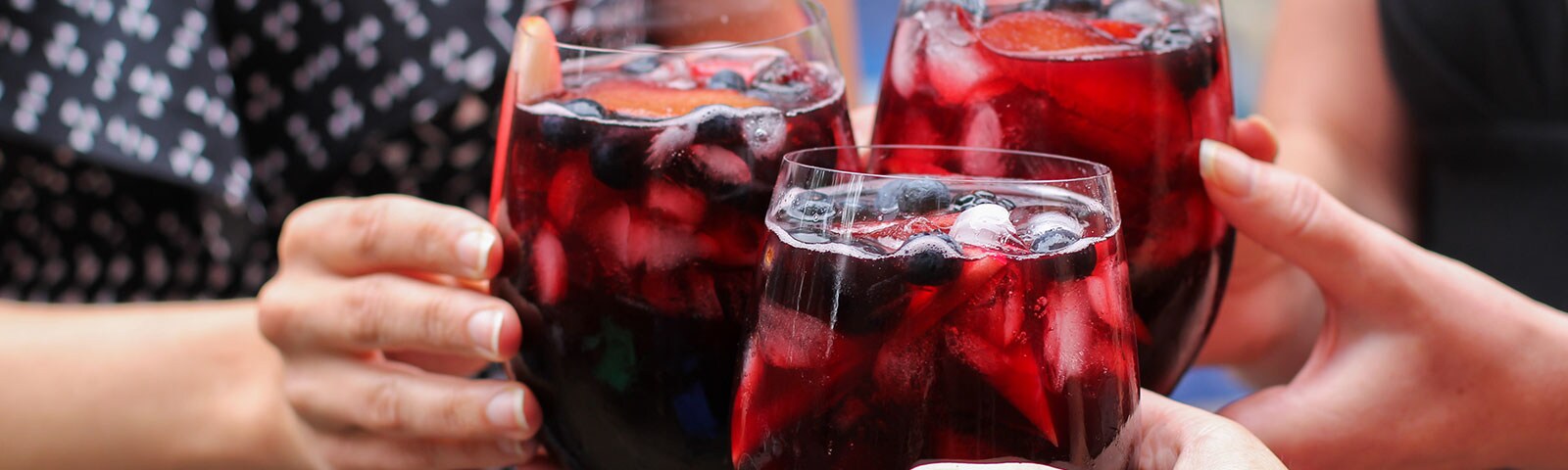 Individuals holding a glass of wine with ice cubes in it Individuals holding a glass of wine with ice cubes in it