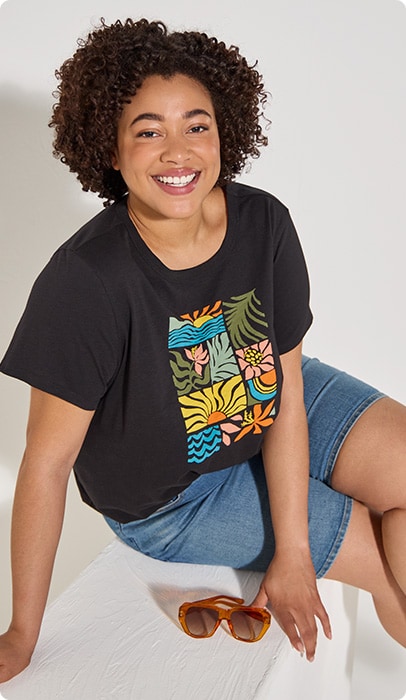 A smiling young woman with a black T-shirt with different nature patterns arranged in rectangles.